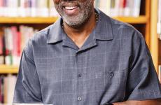 Man dressed nicely wearing glasses and smiling at the camera