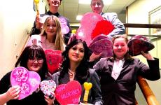 students standing on a stairway holding valentines day hearts