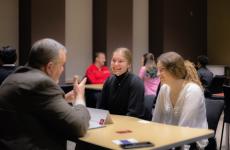 students talking with business professional while seated at a table