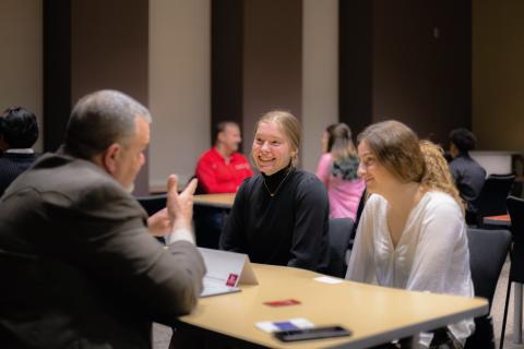 students talking with business professional while seated at a table