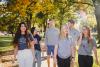 6 people standing on a sidewalk looking at the camera