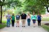 7 people standing on a sidewalk looking at the camera